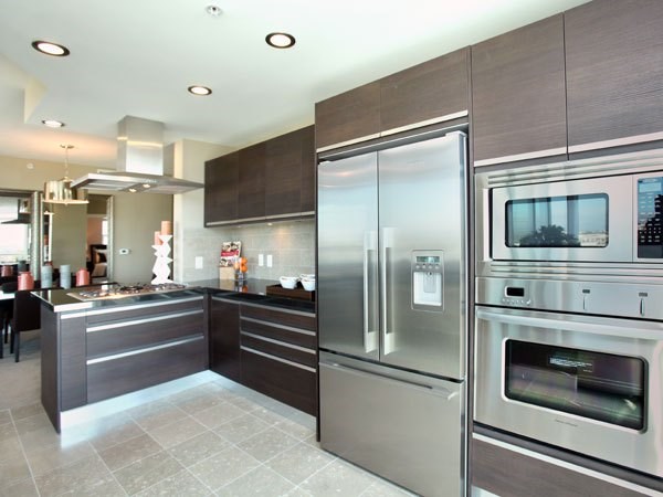 A modern kitchen with stainless steel appliances and a tile floor.
